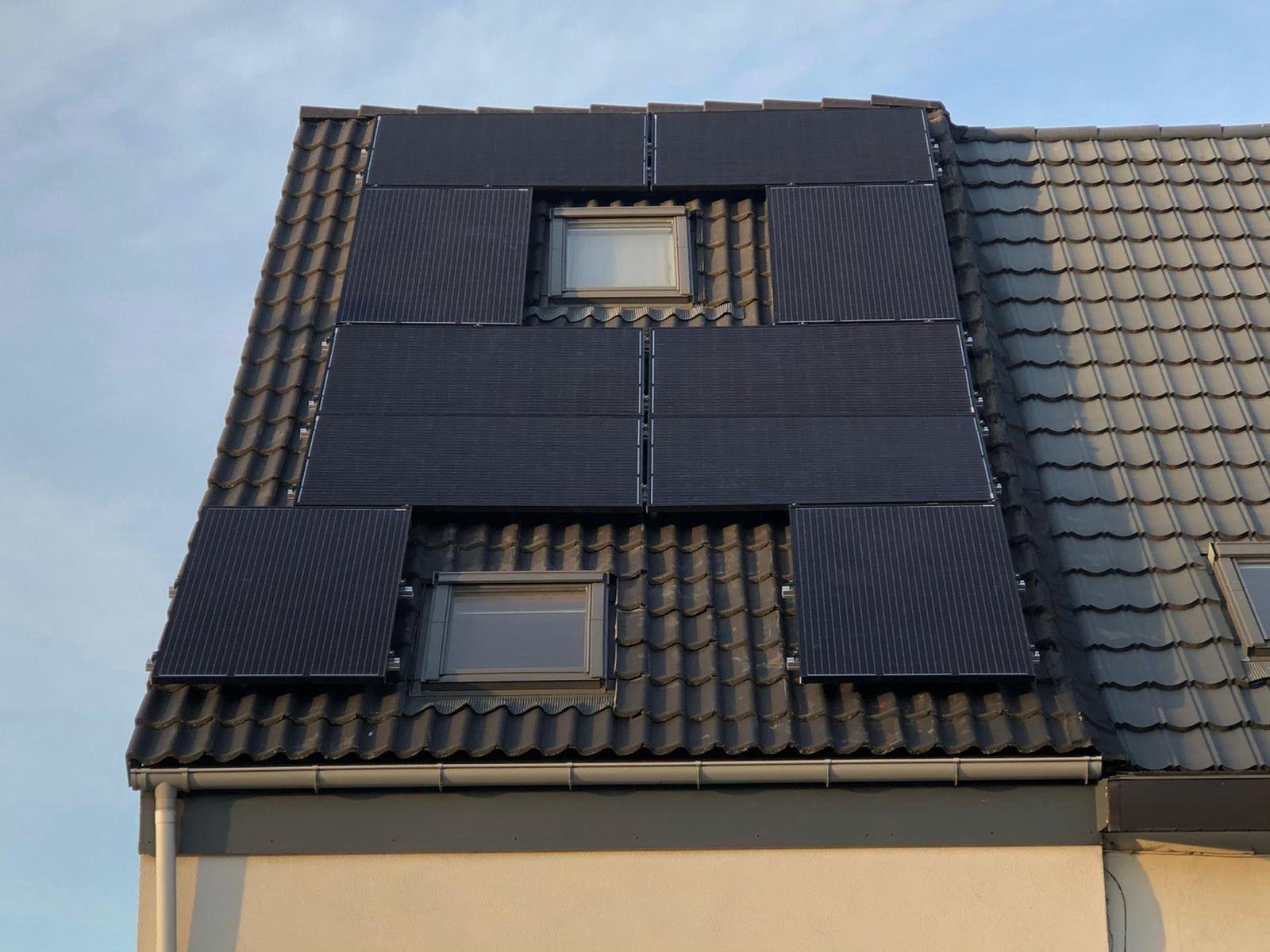 Zonnepanelen strak ingepast rond twee dakvensters op een pannendak