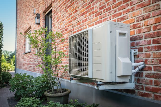 Buitenunit van een warmtepomp geplaatst tegen de gevel van een woning